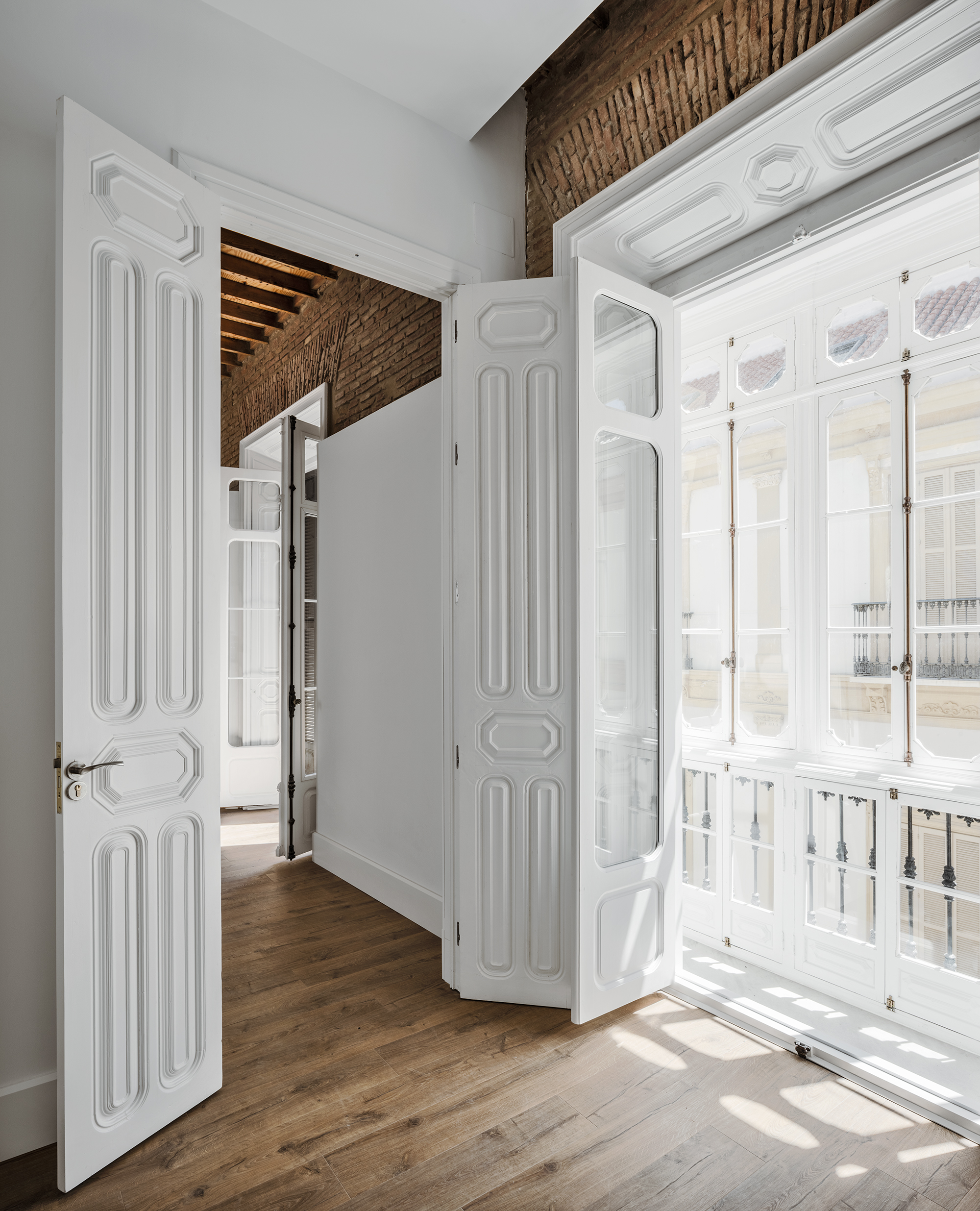 Interior rehabilitado con carpinterías tradicionales, ladrillo visto y lectura de preexistencias arquitectónicas